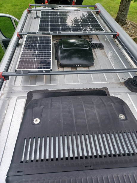 RV rental roof view: two solar panels, a large equipment cover, and another device, all mounted on a sturdy roof rack.