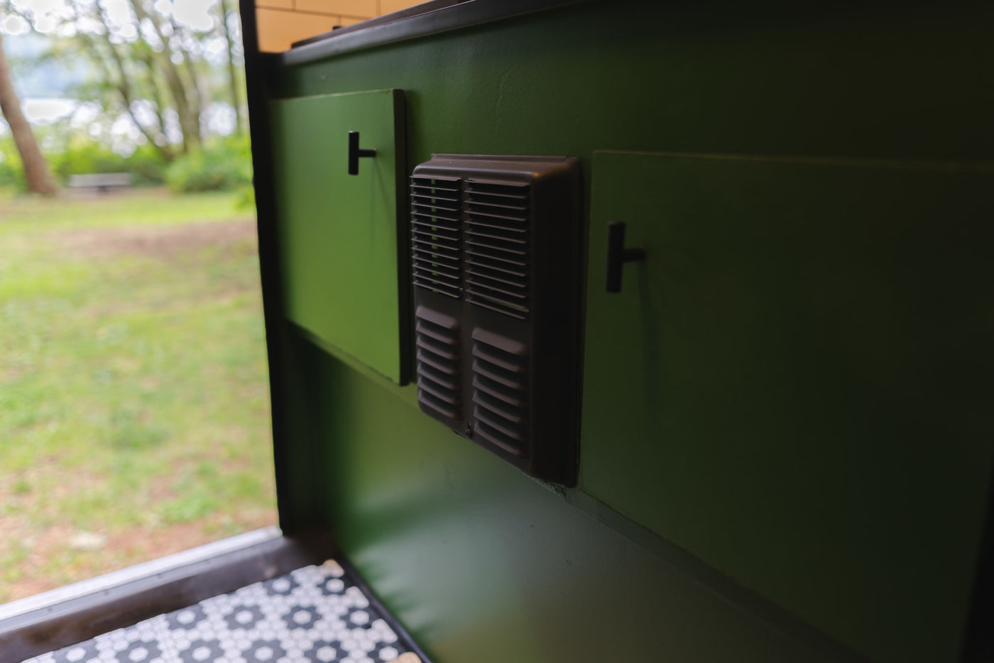 RV rental interior featuring green walls, functional cabinets, a vent, and a welcoming outdoor view. — photo 11