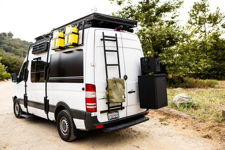 Adventure-ready white Sprinter van rv rental, showcasing side-mounted jerry cans, traction boards, and rear storage.