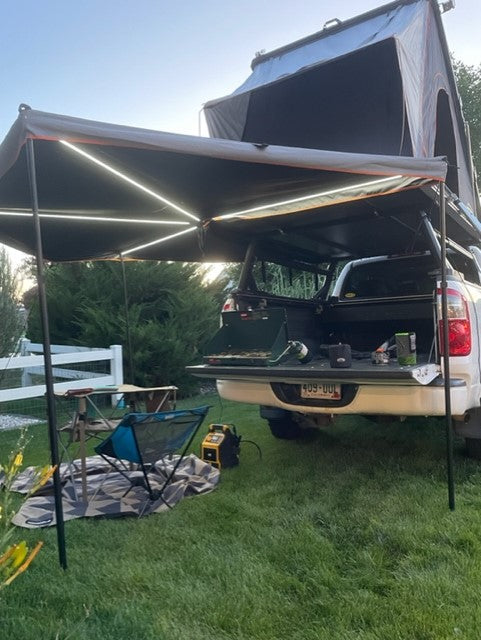 RV rental truck with rooftop tent & illuminated awning provides a cozy camp setup on grass. — photo 9