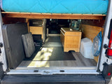 RV rental: organized camper van interior with a raised bed, power system, and smart storage solutions for travel.