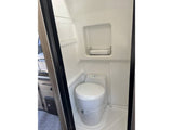 This RV rental's compact bathroom features a white toilet, shower space, and a small storage rack for essentials.