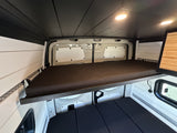 RV rental: Camper van interior showing an elevated bed, lower sleeping area, white paneled walls, and dark ceiling.