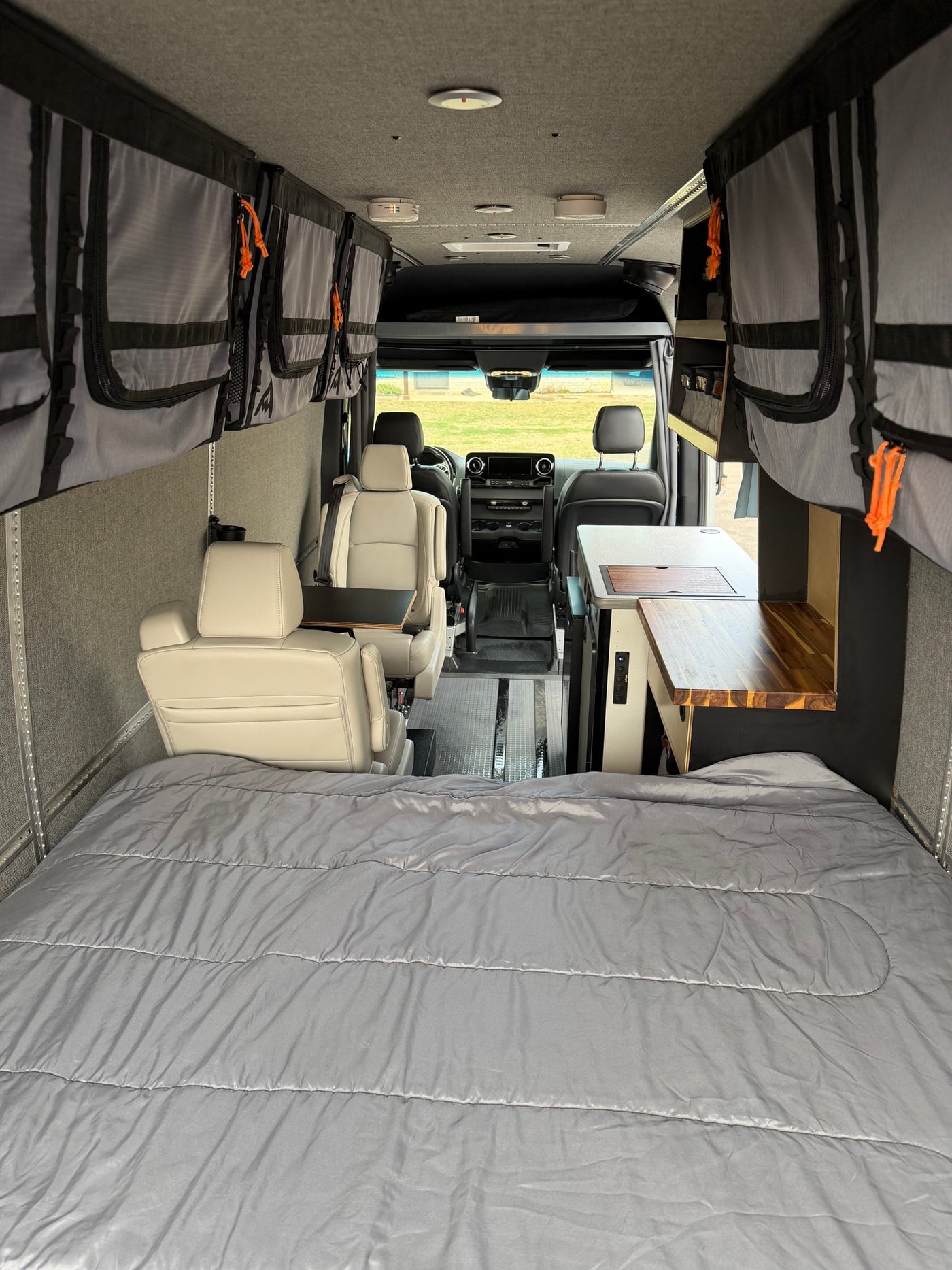 View of a well-appointed RV rental interior with a cozy bed, compact kitchen, and swiveling front seats for comfort. — photo 2