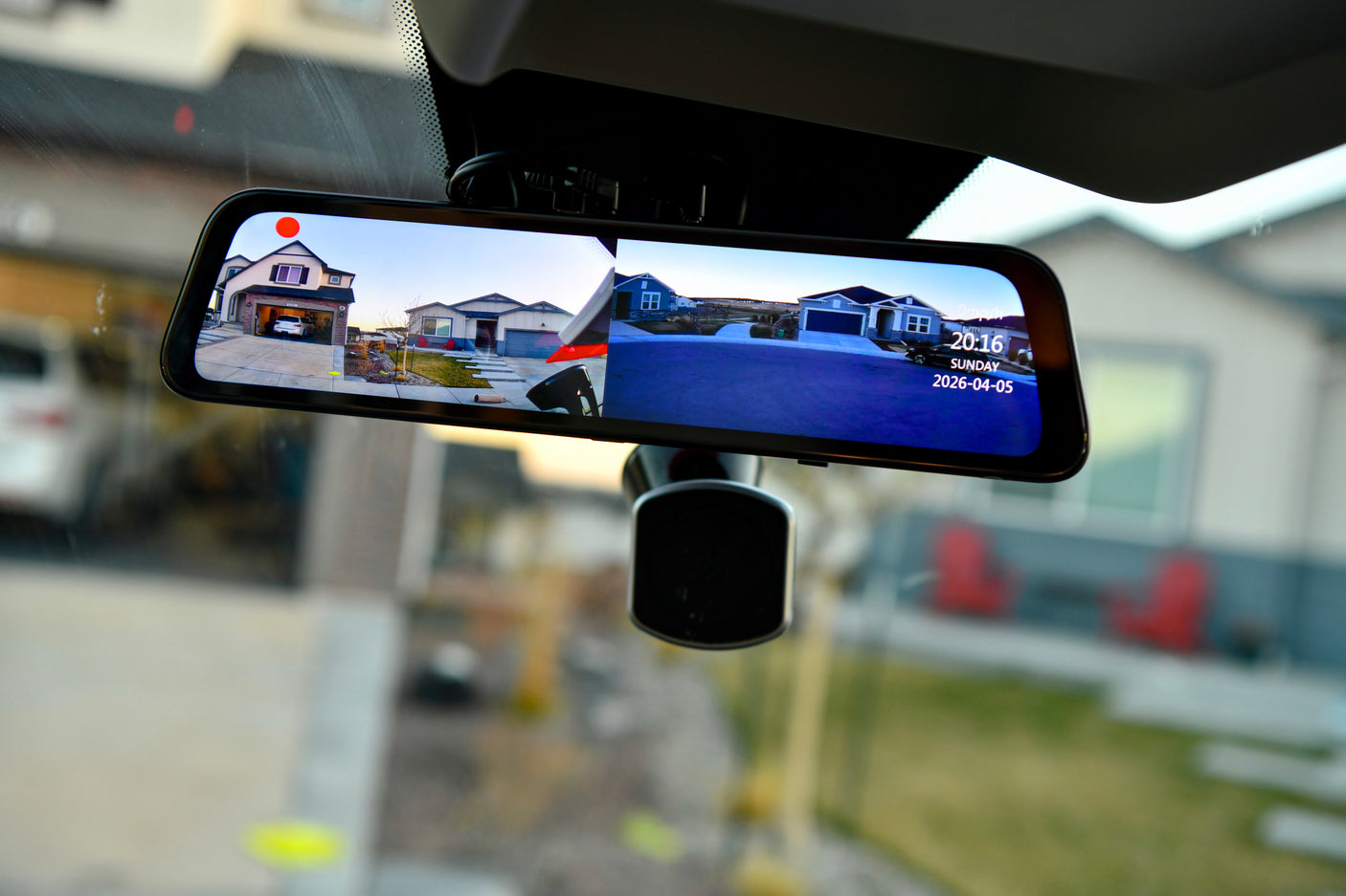 RV rental's smart rearview mirror shows split-screen live feeds of suburban homes, displaying time/date.