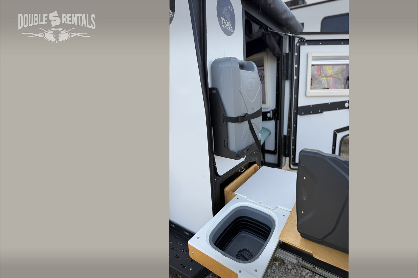 Explore this rv rental's convenient outdoor kitchen, featuring a pull-out sink and mounted water canister for easy camping setup.