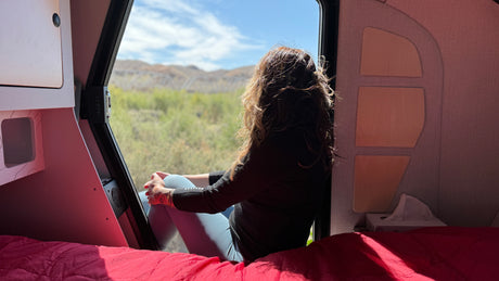 Cozy RV rental interior offers stunning nature views from the comfort of the bed, perfect for nature getaways.