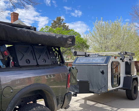 Overland truck with roof awning and compact RV rental, ready for adventure camping.