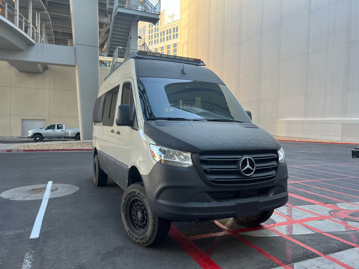  watching a vibrant sunset by an RV rental camper van.|Experience the open road in this rugged Mercedes Sprinter adventure rv rental — photo 2