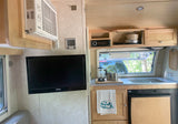 Inside this **rv rental**: a compact kitchen with coffee, sink, and fridge. AC, TV, and stereo add to this cozy camper interior.
