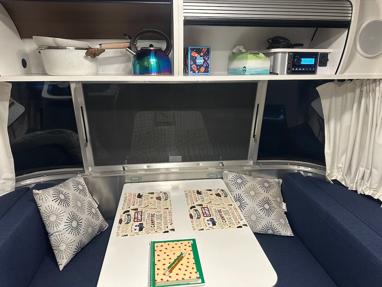 parked in a serene forest setting.|RV rental interior showing a cozy dining area with placemats