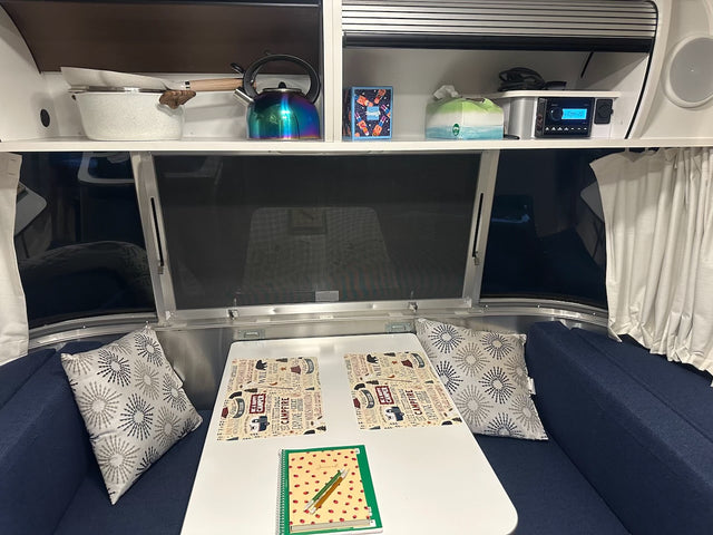  parked in a serene forest setting.|RV rental interior showing a cozy dining area with placemats