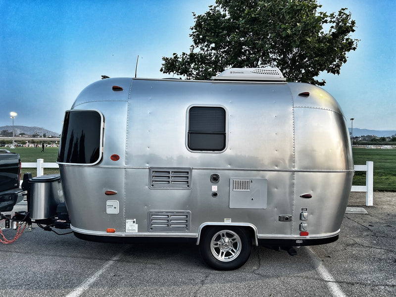 Silver Airstream travel trailer, an iconic RV rental, parked on asphalt with a bright blue sky and green landscape. — photo 4