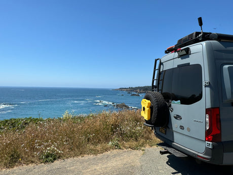 Grey Sprinter camper van by ocean cliff, great rv rental for scenic coastal adventures with breathtaking views.