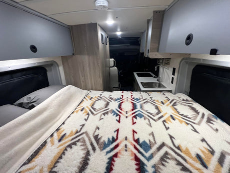 Spacious RV rental interior with comfy bed, kitchen, and ample storage, ready for your road trip.