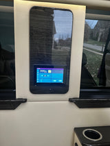 RV rental control panel: smart display in luxury van interior shows lighting, temp, and battery status amidst wood and leather.