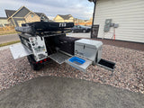 This overland camping trailer, ready for adventure via rv rental, features a rooftop tent, Dometic fridge, and pull-out kitchen.