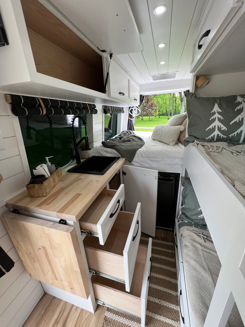 Bright RV rental interior with kitchenette, lower bed, and cozy upper bunk. Perfect for road trips. — photo 10