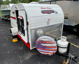 This compact White Water Retro Jr. teardrop RV rental features a patriotic spare tire cover, perfect for adventurers.