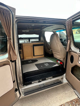 Interior of an RV rental: a cozy camper van with a compact kitchen, front seats, and safety gear.