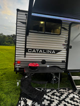 Enjoying a peaceful evening at our RV rental. This Catalina travel trailer features an awning with lights, grill, and outdoor seating.