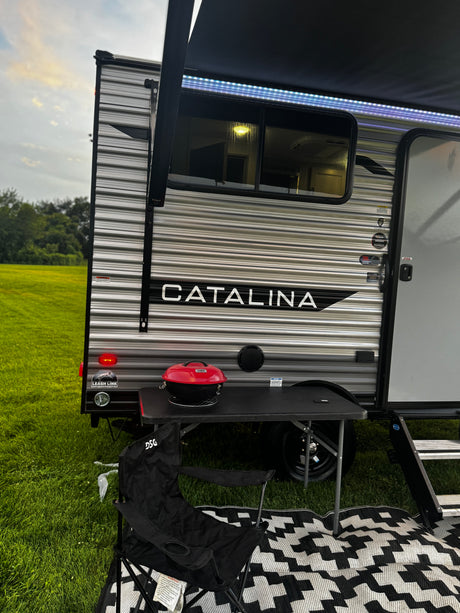 Enjoying a peaceful evening at our RV rental. This Catalina travel trailer features an awning with lights, grill, and outdoor seating.