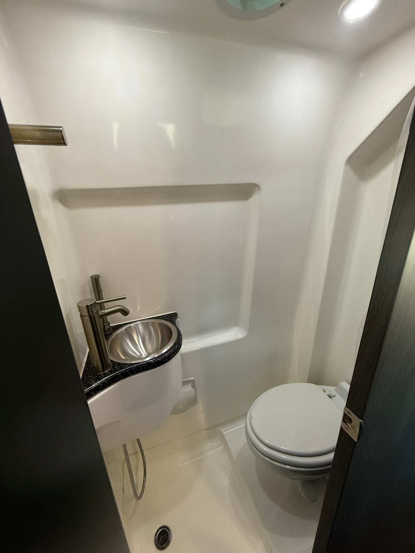 This RV rental features a small, functional bathroom with a shiny stainless steel sink, sleek faucet, and white toilet.