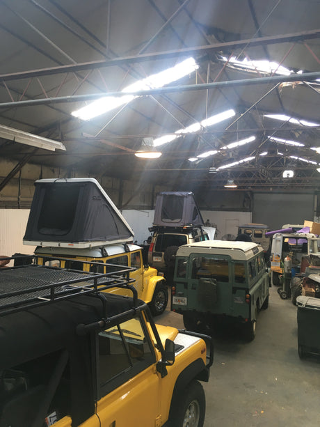 Inside a spacious garage, multiple overlanding SUVs with rooftop tents, ideal for an RV rental adventure, await off-road journeys.