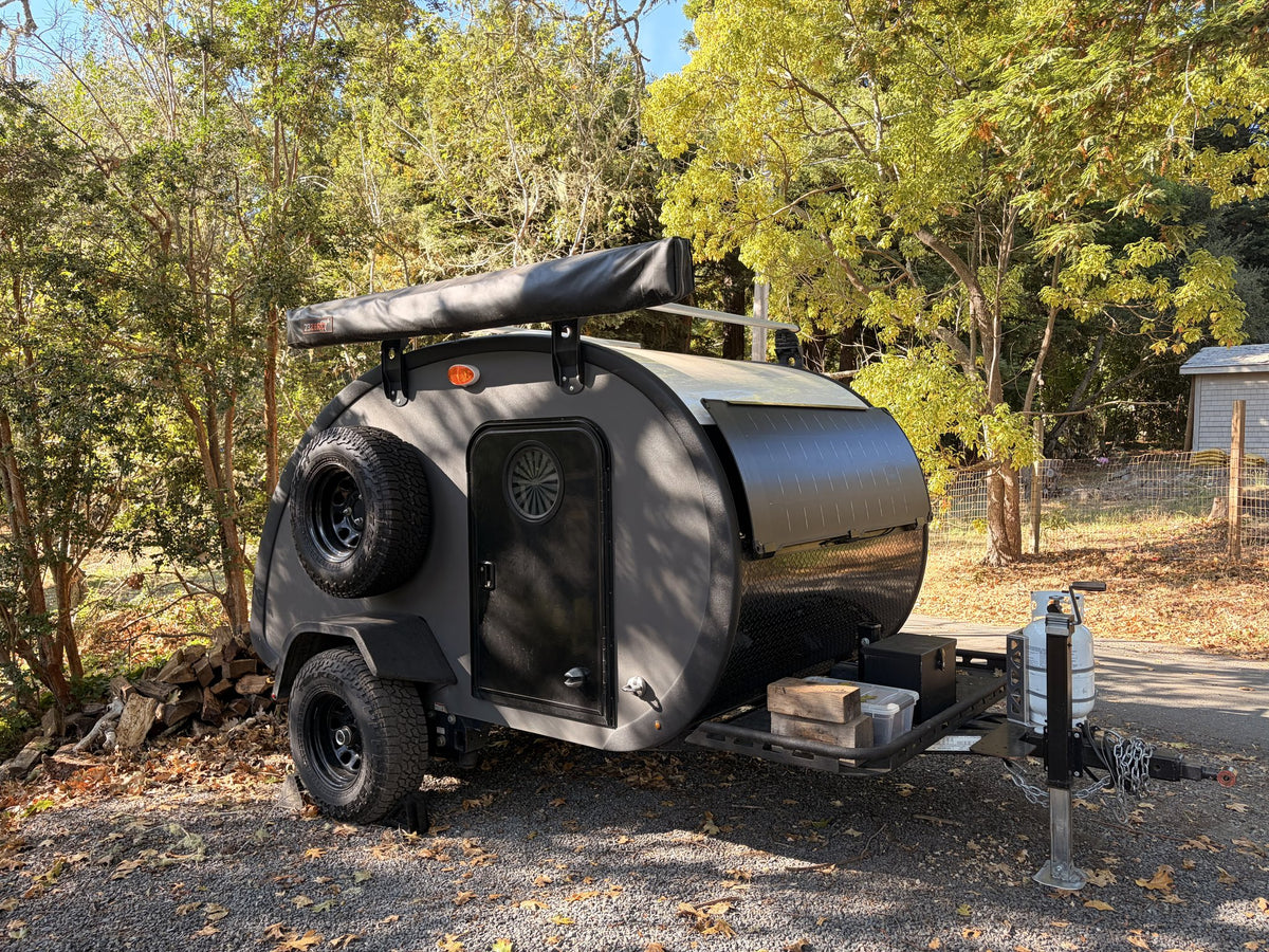 2022 Bean Meaner Bean teardrop camper, dark grey, front three-quarter exterior with roof rack and spare tire