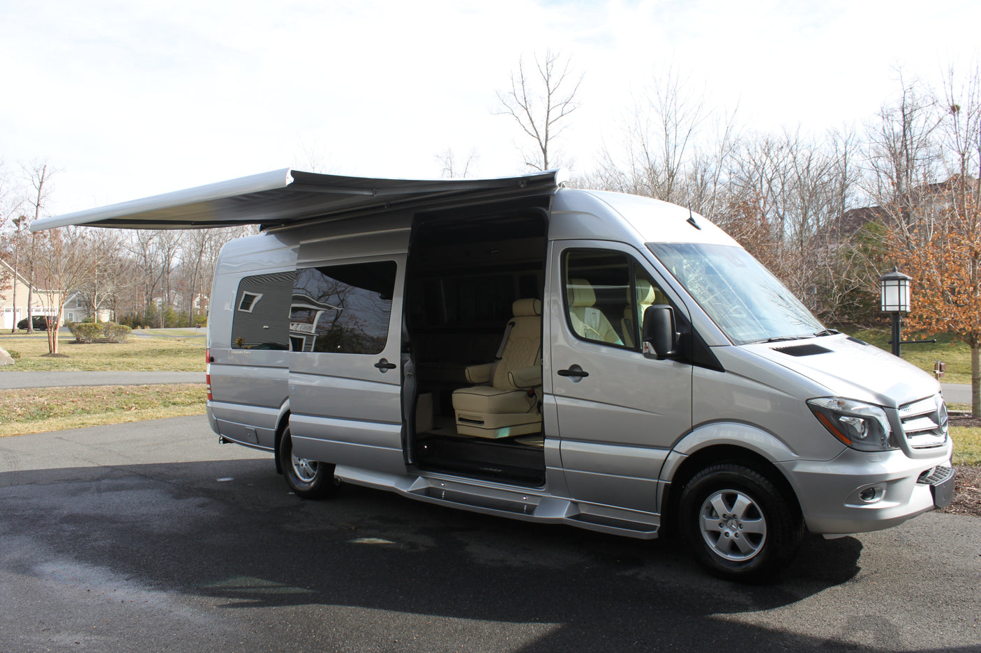 Silver Mercedes Sprinter RV rental with open door & extended awning. Luxury camper van for travel.