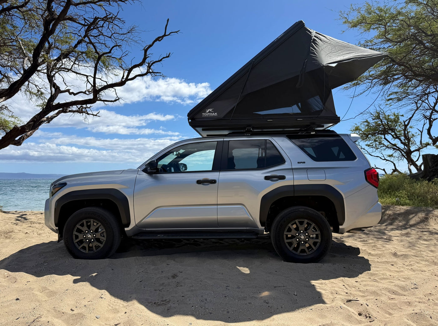 set against scenic mountains.|RV rental: Silver SUV with open TOPOAK rooftop tent on a sandy beach by the ocean — photo 2