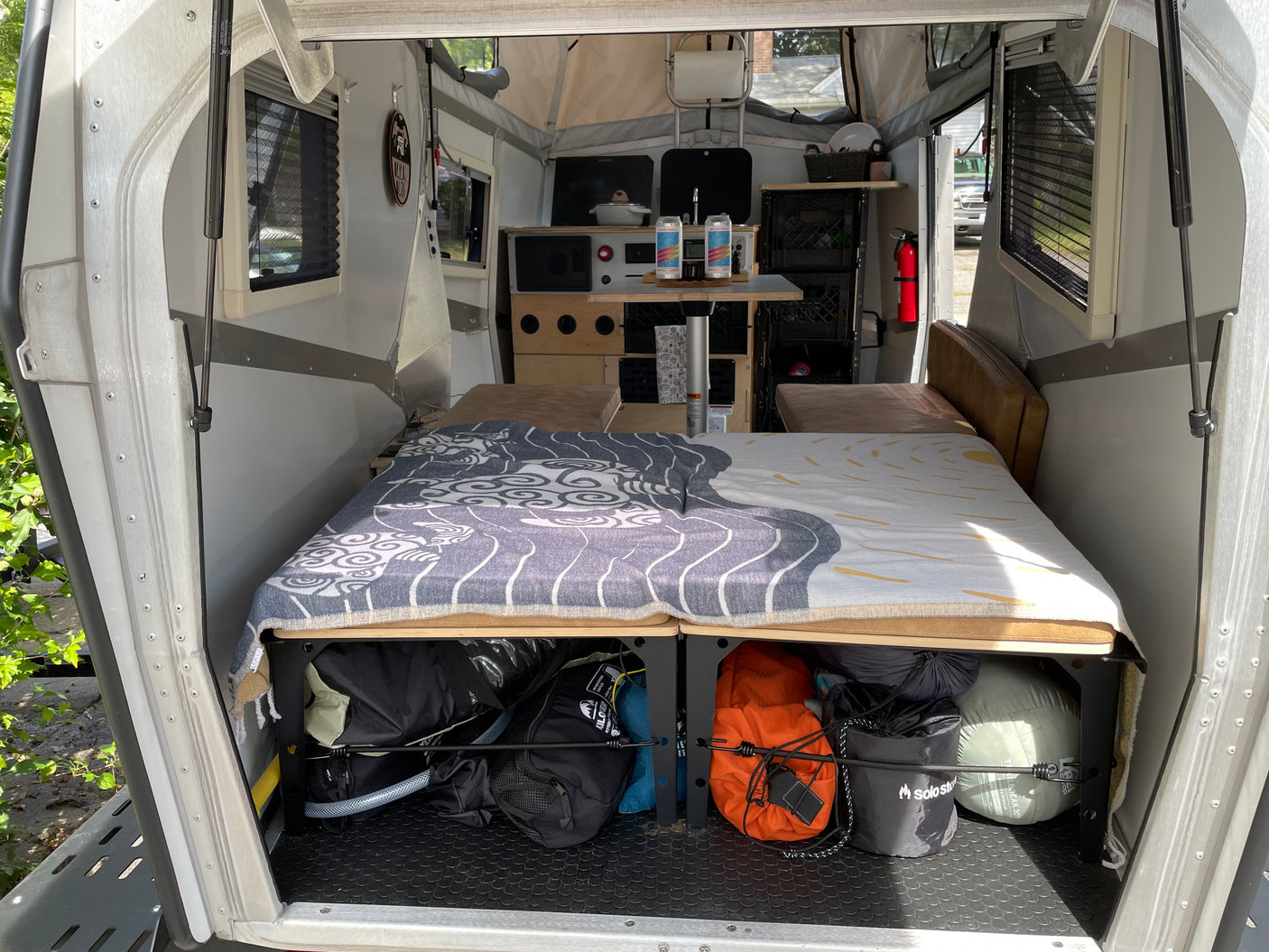Spacious RV rental interior: cozy bed, compact kitchen, & ample storage visible from the rear, ready for adventure.