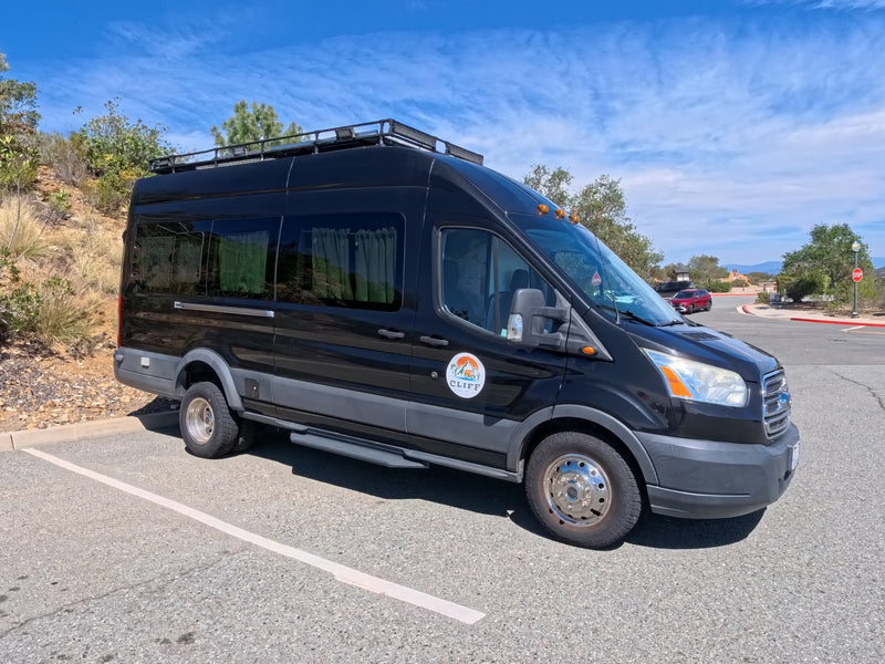  ready for adventure travel.|Black Ford Transit campervan RV rental with a roof rack — photo 2