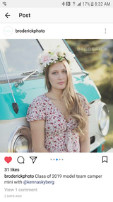 Young woman with flower crown poses in a floral dress beside a teal vintage RV rental. A senior model photoshoot.