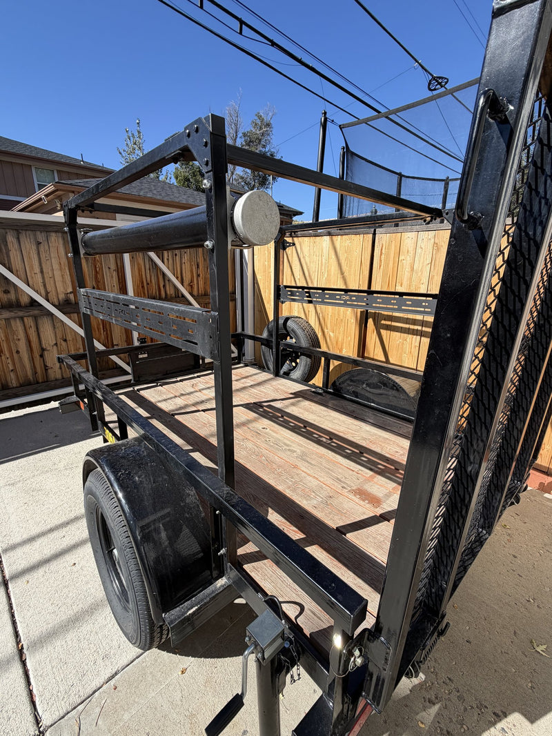Elevated angle over the deck showing the overhead rack frame, the dropped mesh gate, the spare tire and the full run of the wood-plank floor — photo 10