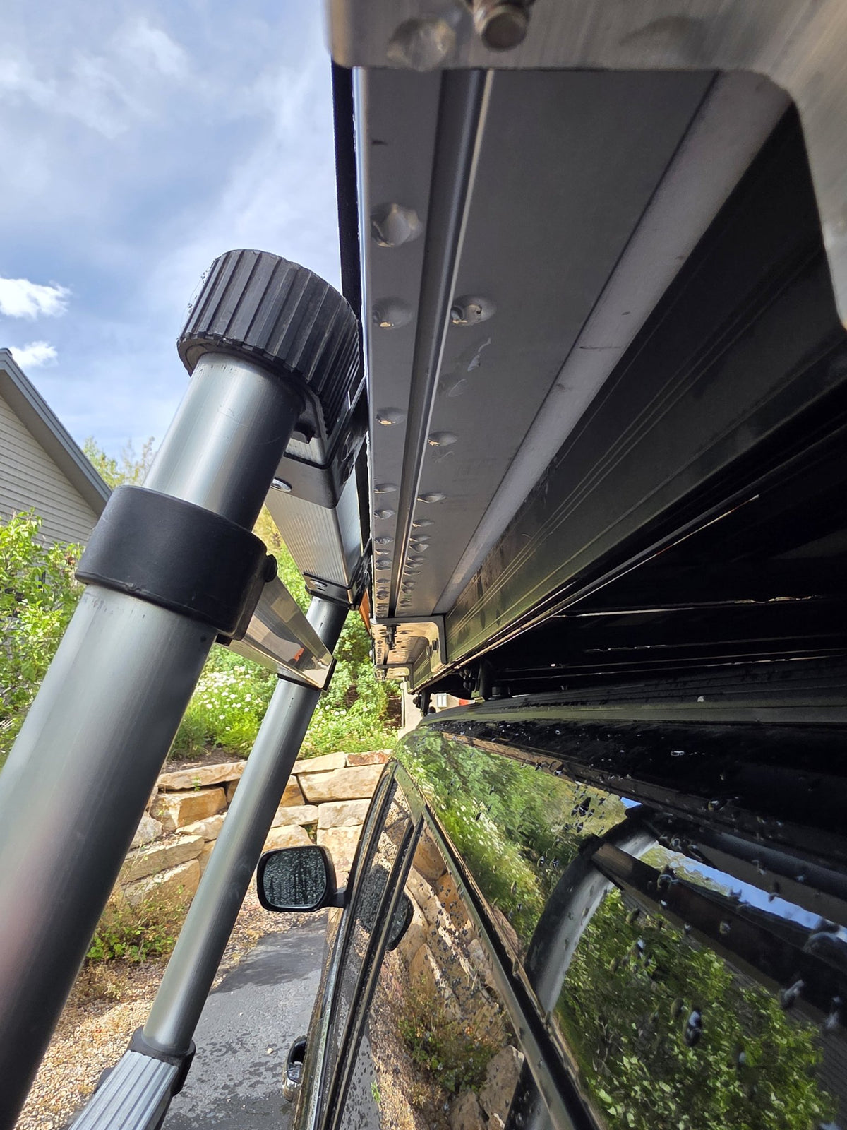 Close detail of the Terrapod RTTx XL mounting hardware and shell rail, showing the bolted aluminium extrusion, the T-slot accessory track and the telescoping ladder stowed alongside — photo 12
