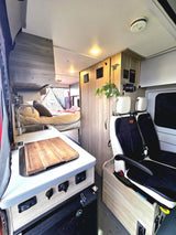 This RV rental features a well-equipped campervan interior with kitchen, bed, seating, and controls. Compact and ready for travel.