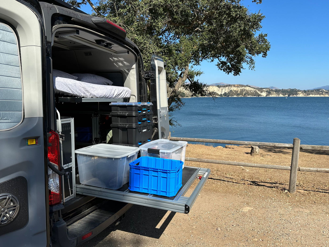 parked by a scenic coast.|RV rental's integrated portable water and shower system. Features Reliance jug — photo 3