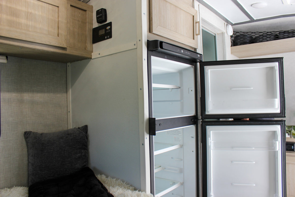  and a glass pitcher of green stalks on the white countertop.|Compact RV rental kitchen features a stainless steel sink — photo 38