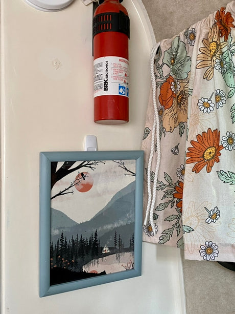 RV rental interior featuring a fire extinguisher, framed art, and floral fabric for safety and cozy decor.