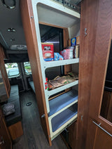 Inside an RV rental: a convenient pull-out pantry stocked with snacks & coffee, optimizing small space living for your trip.