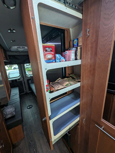 Inside an RV rental: a convenient pull-out pantry stocked with snacks & coffee, optimizing small space living for your trip.