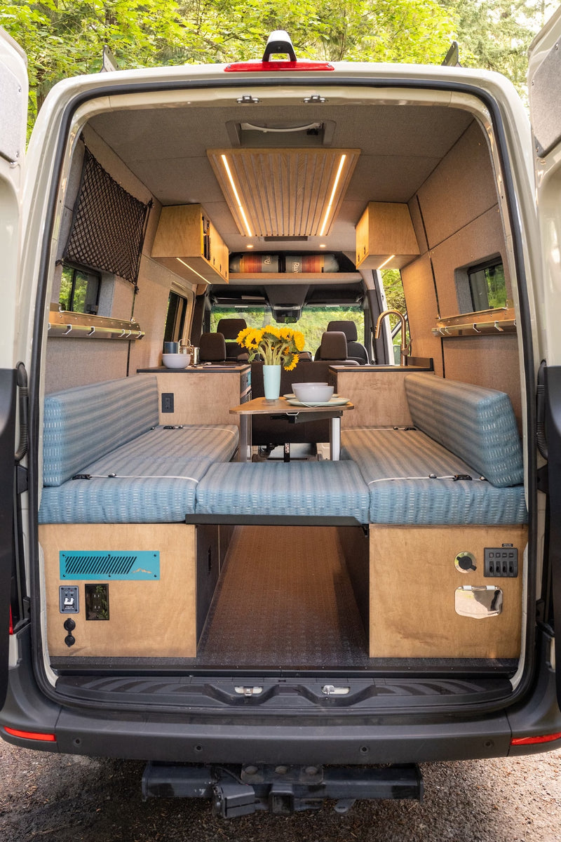 RV rental: Well-appointed camper van interior with adaptable seating, kitchen, overhead storage, and rear garage. — photo 19