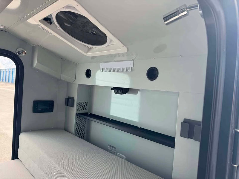 Interior cabin of the XPedition Voyager Sky XE looking toward the galley wall, with the mattress cushion, MaxxAir roof fan overhead, reading light, control panel and overhead shelf — photo 7