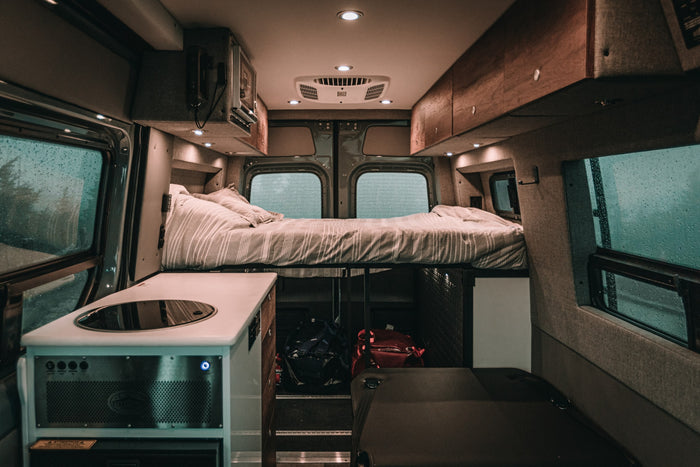  ready for your next RV rental adventure on a rainy day. Shows the dashboard and infotainment.|Cozy RV rental interior showing a comfortable bed with striped bedding