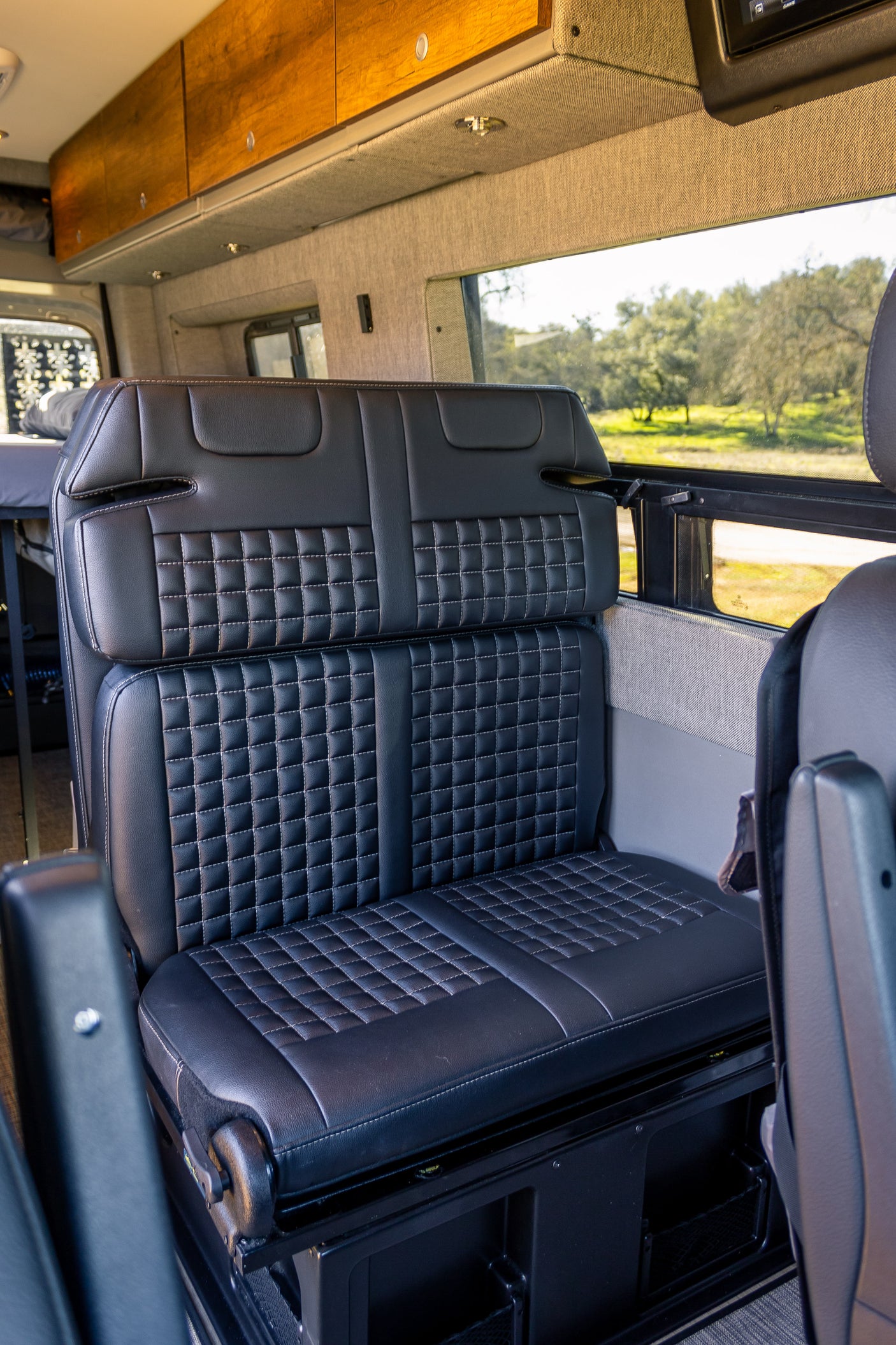 Comfortable seating in an rv rental: featuring stylish black quilted bench seats and ample overhead cabinets.
