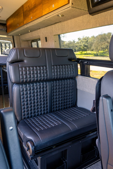 Comfortable seating in an rv rental: featuring stylish black quilted bench seats and ample overhead cabinets.