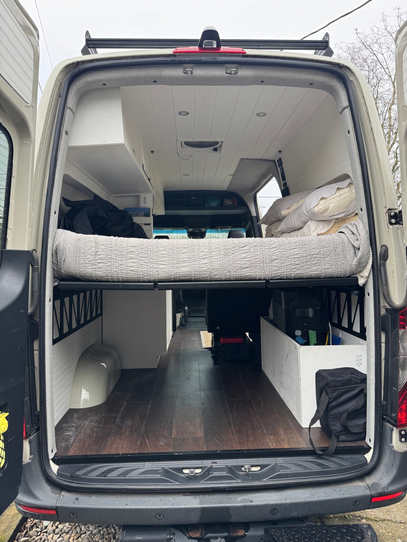 Back of an RV rental: cozy camper van interior with raised bed, wooden floor, and ample storage for your adventures.