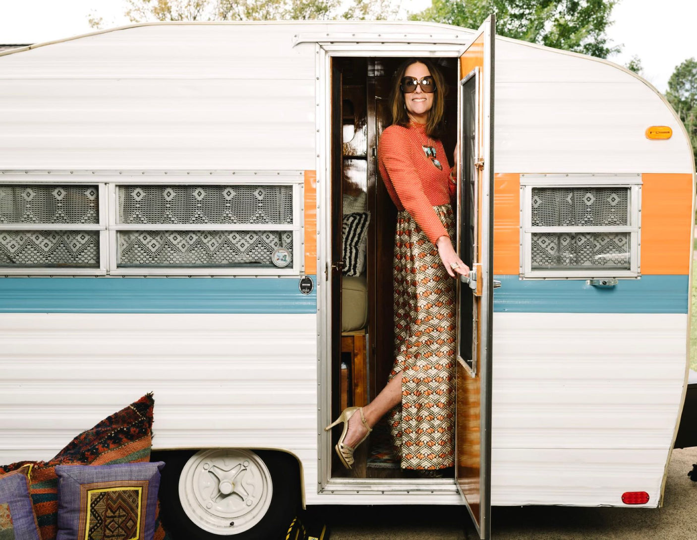 Stylish woman steps out of a colorful vintage RV rental, ready for adventure.