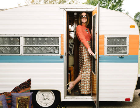 Stylish woman steps out of a colorful vintage RV rental, ready for adventure.